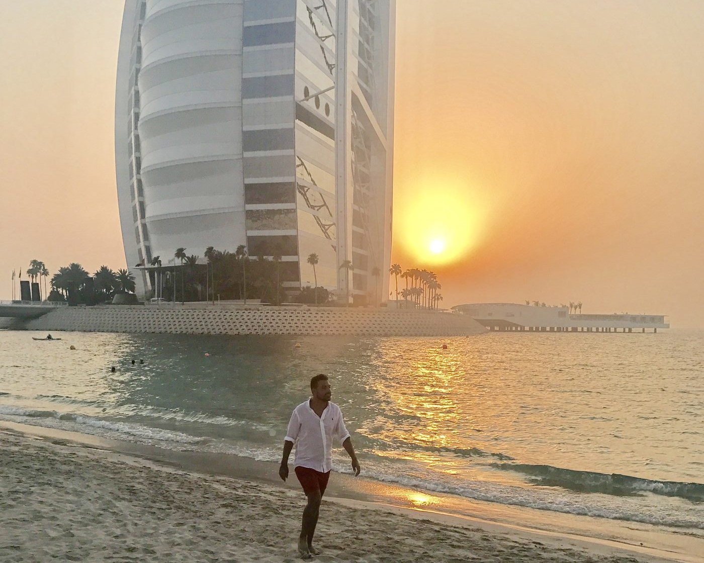 Mattia Ferro sulla spiaggia davanti al Burj Al Arab a Dubai, al tramonto.